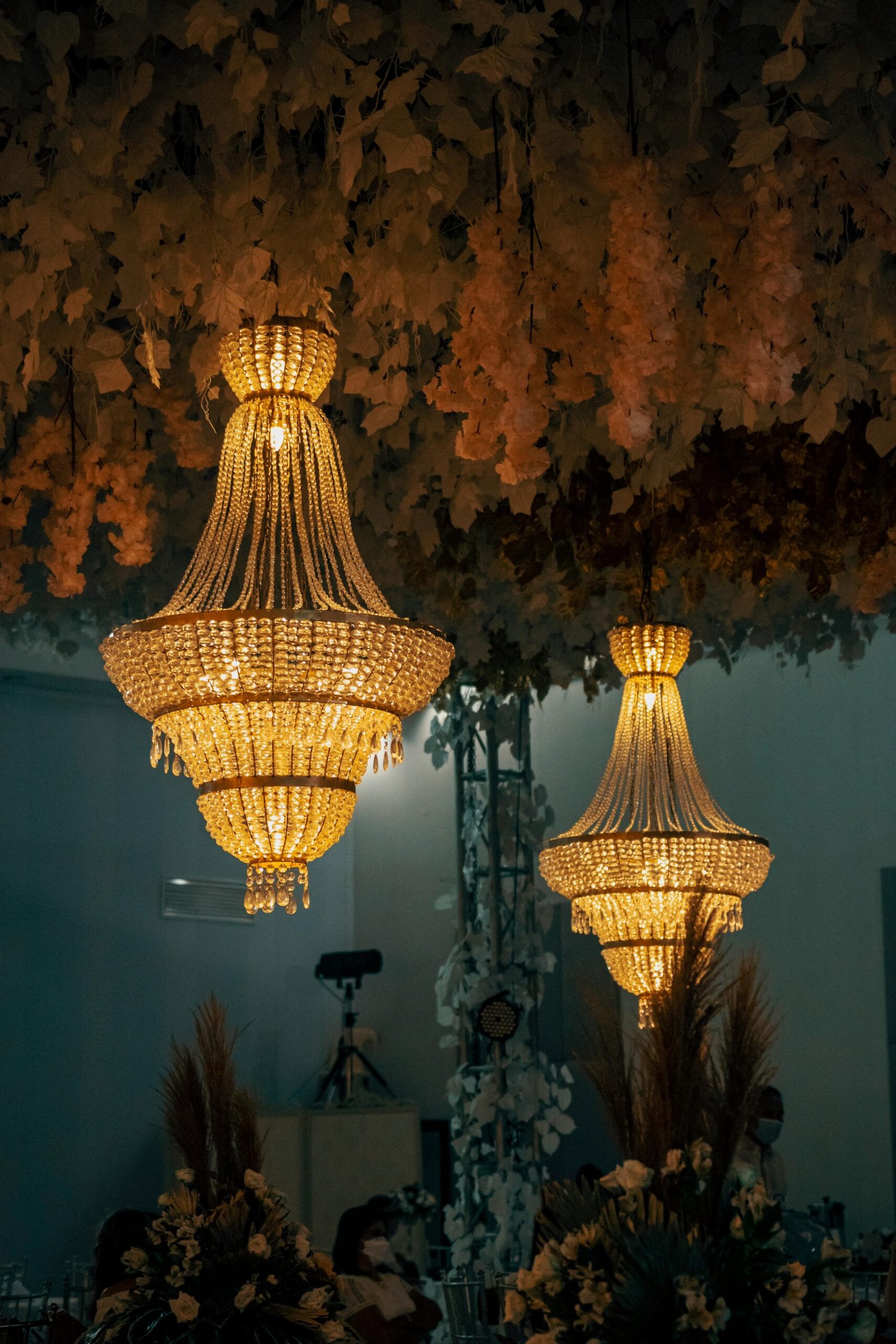Two beautifully lit crystal chandeliers hang in a luxurious room, creating a warm, inviting atmosphere.