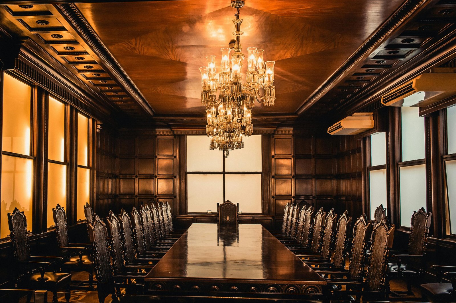 Luxury dining room featuring a grand chandelier, wooden table, and ornate chairs.