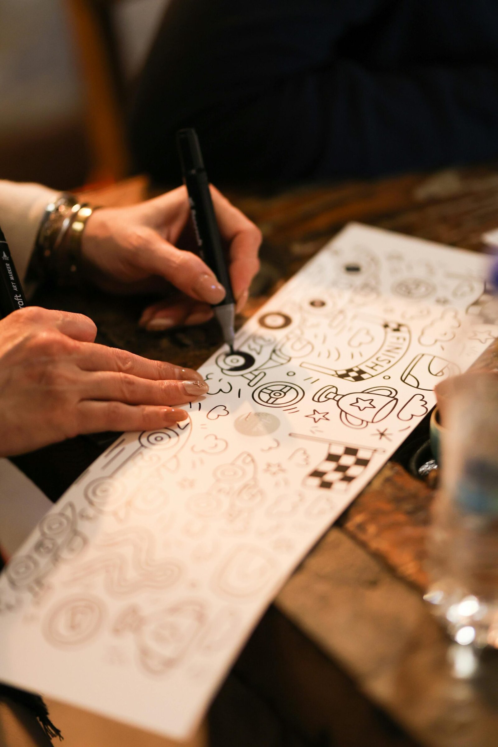 Close-up of hand drawing doodles on paper in a creative workshop setting.