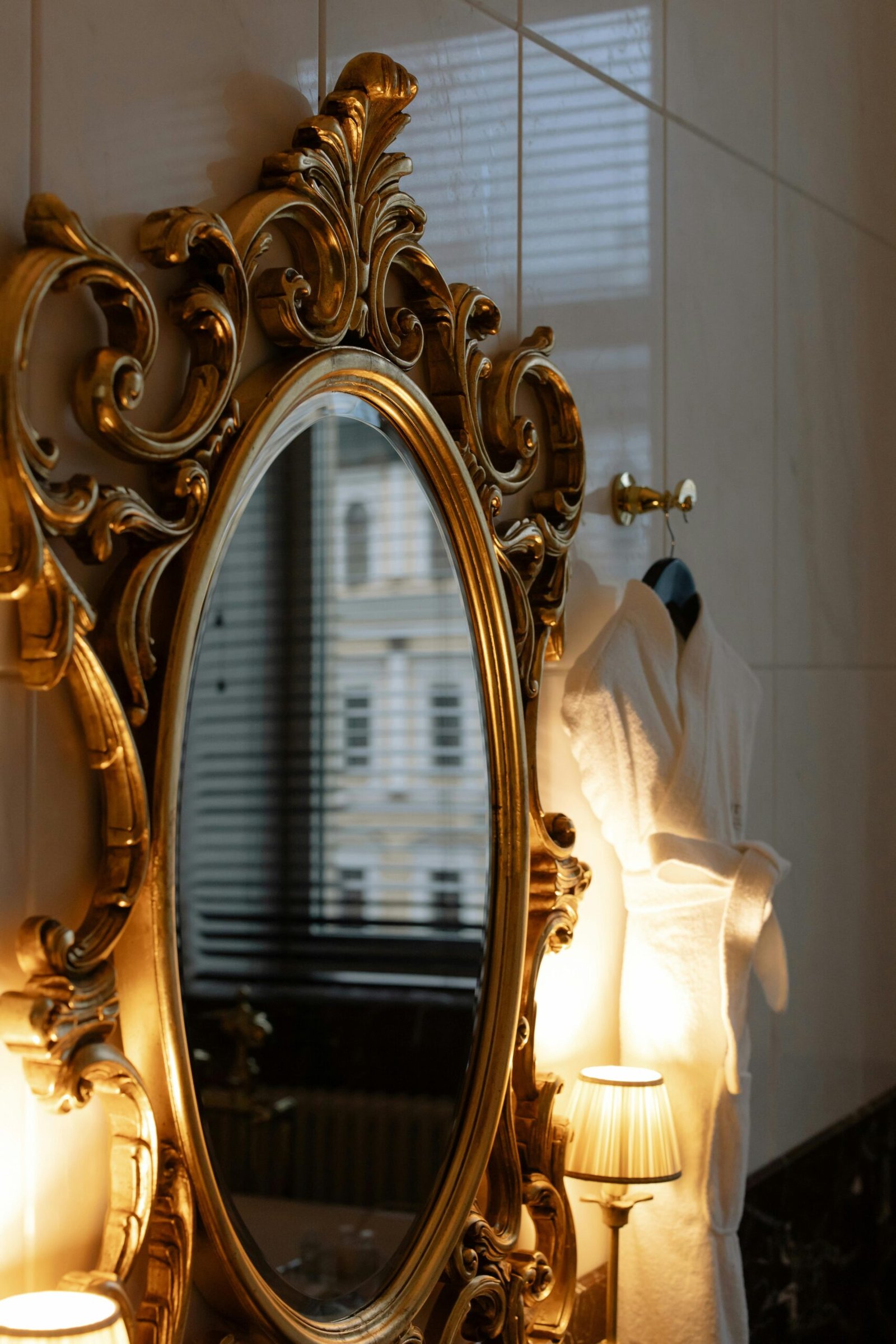 Luxurious gold framed mirror reflects a cozy interior with warm lighting and elegant decor.