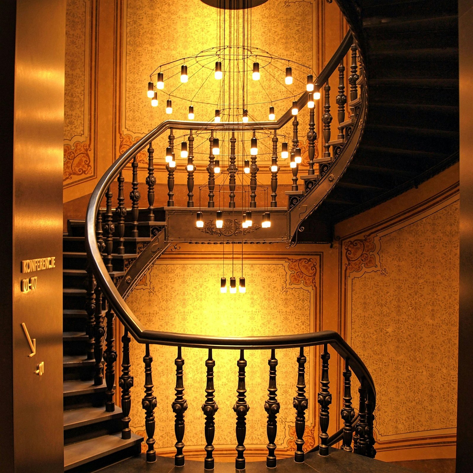 Luxurious spiral staircase with ornate chandelier and decorative details in a hotel setting.