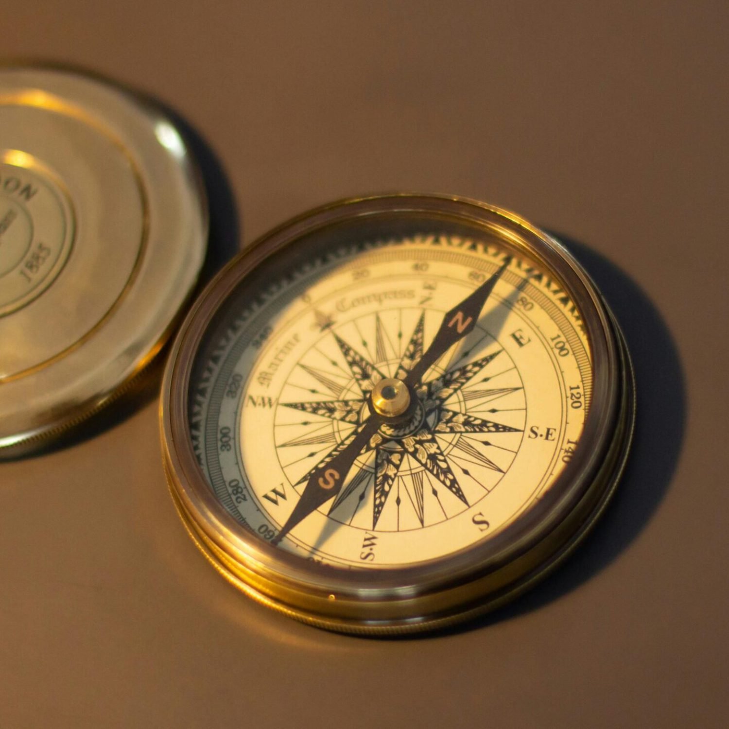 A close-up of a vintage brass compass on a warm brown surface, perfect for exploration themes.
